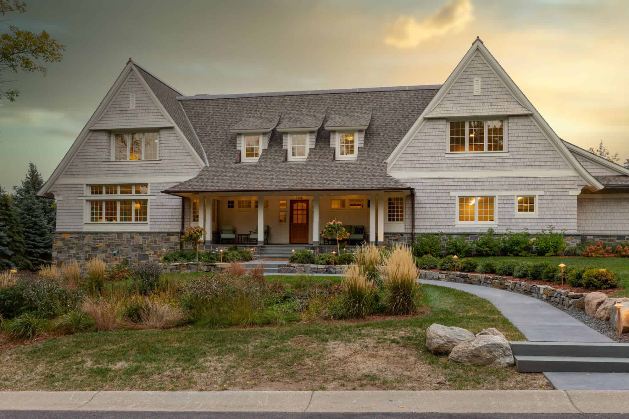 picture of a charming house with stone accents and a shingled roof.